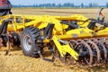 Hitch of a powerful multi-row disc harrow with a tractor on the background of an agricultural field