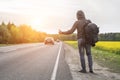 A hitchhiker catches a car on the road