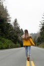 hitchhiker girl back view in coat walking on highway, travel