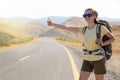 Hitchhiker traveler woman on the road in sunset. Girl traveler hiker on the road. Summer vacation. Freedom. Royalty Free Stock Photo