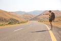 Hitchhiker traveler woman on the road in sunset. Girl traveler hiker on the road. Summer vacation. Freedom. Royalty Free Stock Photo