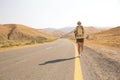 Hitchhiker traveler woman on the road in sunset. Girl traveler hiker on the road. Summer vacation. Freedom.