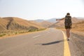 Hitchhiker traveler woman on the road in sunset. Girl traveler hiker on the road. Summer vacation. Freedom. Royalty Free Stock Photo