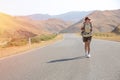 Hitchhiker traveler woman on the road in sunset. Girl traveler hiker on the road. Summer vacation. Freedom.