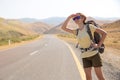 Hitchhiker traveler woman on the road in sunset. Girl traveler hiker on the road. Summer vacation. Freedom.