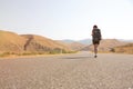 Hitchhiker traveler woman on the road in sunset. Girl traveler hiker on the road. Summer vacation. Freedom.