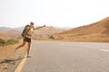 Hitchhiker traveler woman on the road in sunset. Girl traveler hiker on the road. Summer vacation. Freedom. Royalty Free Stock Photo