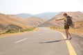 Hitchhiker traveler woman on the road in sunset. Girl traveler hiker on the road. Summer vacation. Freedom. Royalty Free Stock Photo