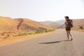 Hitchhiker traveler woman on the road in sunset. Girl traveler hiker on the road. Summer vacation. Freedom. Royalty Free Stock Photo