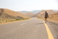 Hitchhiker traveler woman on the road in sunset. Girl traveler hiker on the road. Summer vacation. Freedom. Royalty Free Stock Photo