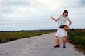 Hitchhiking country girl on rural road Royalty Free Stock Photo