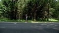 Hitchhiking woman with backpack on road on fores background