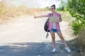 Hitchhiking woman travel. Beautiful cheerful young woman with a cardboard in her hands catches a passing car showing