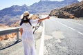 Hitchhiking woman travelling by hitchhike on road side, smiling happy on summer vacation