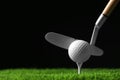 Hitting golf ball with club on artificial grass against black background Royalty Free Stock Photo