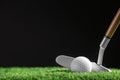 Hitting golf ball with club on artificial grass against black background Royalty Free Stock Photo