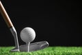 Hitting golf ball with club on artificial grass against black background Royalty Free Stock Photo