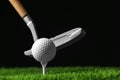 Hitting golf ball with club on artificial grass against black background, space for Royalty Free Stock Photo