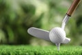 Hitting golf ball with club on artificial grass against blurred background Royalty Free Stock Photo