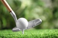 Hitting golf ball with club on artificial grass against blurred background, space for Royalty Free Stock Photo