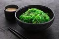 Hiyashi Wakame Chuka seaweed salad with sesame seeds in a black bowl and peanut sauce Royalty Free Stock Photo