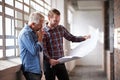 Hm, where to begin. two male architects discussing blueprints while standing indoors. Royalty Free Stock Photo