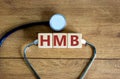 HMB symbol. Wooden cubes with the words `HMB - heavy menstrual bleeding` and stethoscope. Medical and HMB concept. Copy space