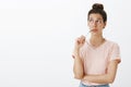 Hmm might work. Portrait of unsure hesitant cute tanned female with messy bun biting frame of eyewear gazing at upper Royalty Free Stock Photo