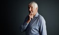 Hmm...Studio shot of a handsome mature man looking thoughtful against a dark background. Royalty Free Stock Photo