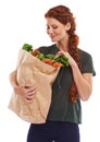 Hmmm... what am I going to do with these. Studio shot of a beautiful young woman holding a shopping bag full of fresh