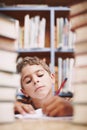 Hmmm.... A young boy doing some creative writing between a stack of books. Royalty Free Stock Photo