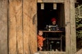 Hmong hill tribe woman uses sewing machine while her daughter poses for photo Royalty Free Stock Photo