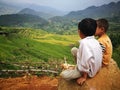 Hmong Miao minority children sitting on a rock at a valley of yellow rice paddy field
