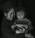 Hmong tribe old lady holding her grandson in her arms inside her house, Sapa Vietnam