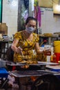 Ho Chi Minh City, Vietnam- November 9, 2022: Street food store in the streets of Saigon. Female chef cooking or bbq on open fire,