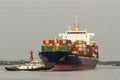 Tugboat Pushing A Large Container Ship To Harbour For Unload.