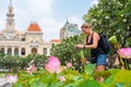 Ho Chi Minh City, Vietnam: a traveler takes a photo of pink lotus flowers in garden in front of Saigon City Hall