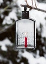 Hoarfrost covered black iron lantern with red candle init hanging in the winter garden. Royalty Free Stock Photo