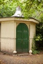 Historic timber garden shed with eight sides and green doors and metal structure on roof