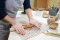 Hobbies concept - A woman ceramist rolls clay with a rolling pin in a pottery workshop
