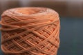 A coil of large knitted yarn of peach color on the blure backgroud