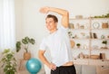 Hobbies in free time and healthy lifestyle. Attractive man smiling and doing exercises in living room Royalty Free Stock Photo