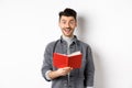 Hobbies and leisure. Happy young man reading planner, holding diary or red journal and smiling, making notes, standing