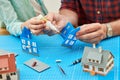 Hobby of building scale miniature model of house. Dad with child gluing a small plastic home