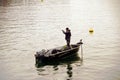 A hobby fisherman on the lake Zurich in winter. He is standing in a boat and there is a yellow buoy.