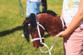 Hobby horsing competition on a green grass, hobby horse riders jumping, equestrian sport training with stick toy horses in a