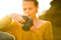 Outdoor lifestyle portrait of young woman taking photos with her mirrorless camera