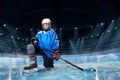 Hockey player with stick standing on one knee Royalty Free Stock Photo