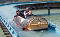 Children sailing in a boat in the form of a log on a waterway in a recreation park Royalty Free Stock Photo