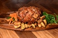 Hog roast pork decorated with patatos and veg on wooden board and kitchen table Royalty Free Stock Photo